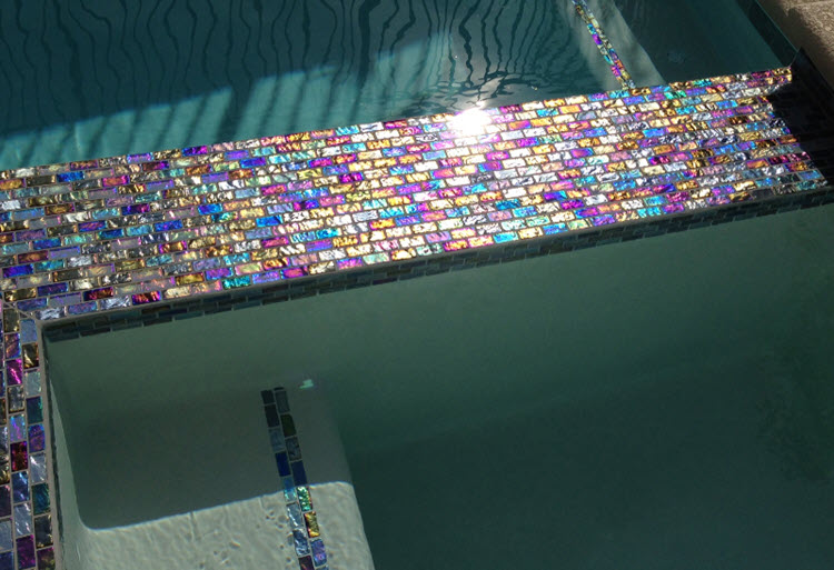 Brick iridescent mosaics outline the pool step for guidance in stepping in and out of the pool.