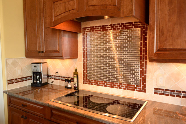 A dramatic backsplash focal design created with an offset metal mosaic framed with a red glass mosaic border