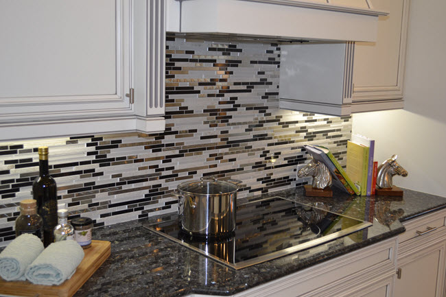 A backsplash featuring mosaic made from Carrara White Marble, metal and dark glass sticks